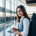 Young woman waiting at Alicante airport with a tablet and carry-on luggage.